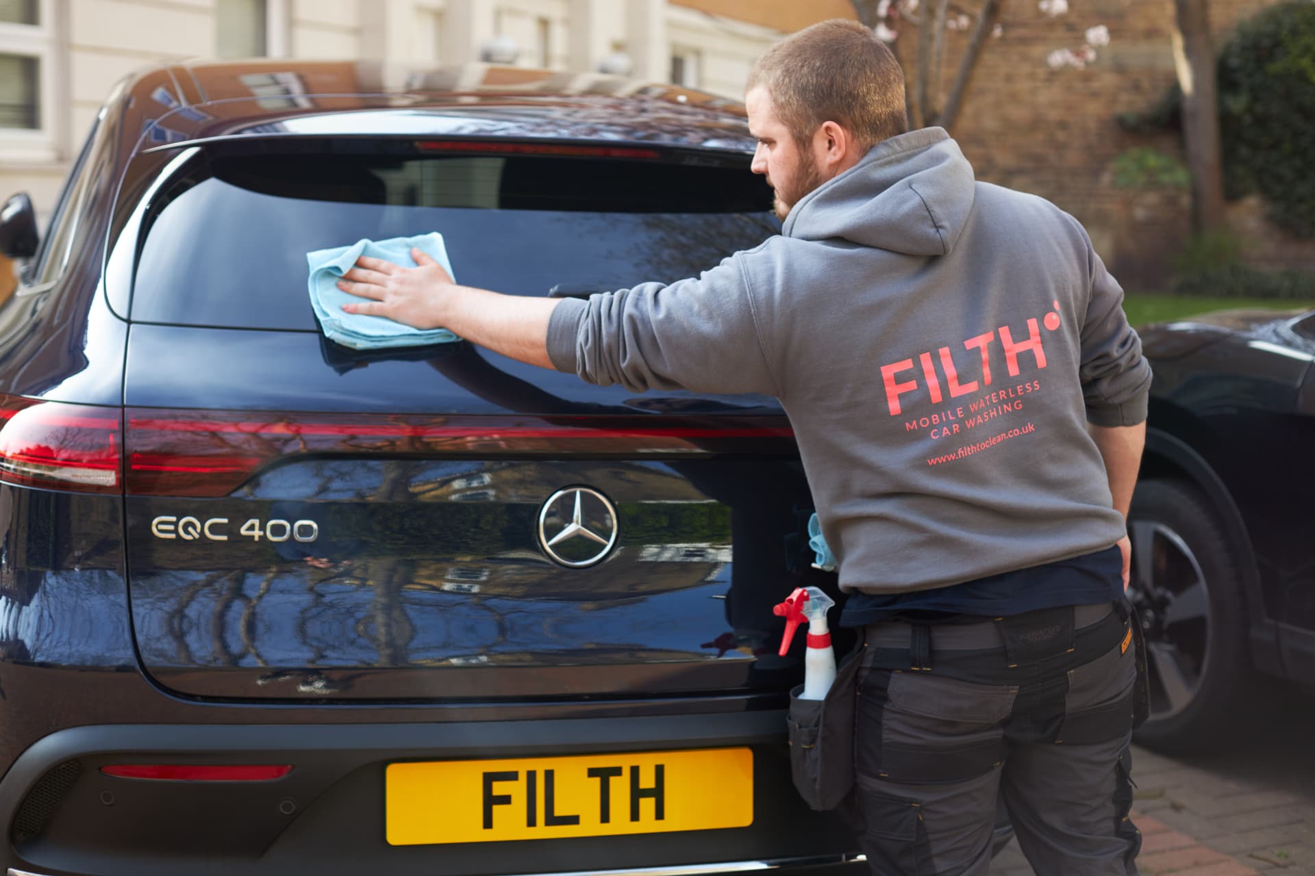 A Filth technician waterless-cleaning a car on site