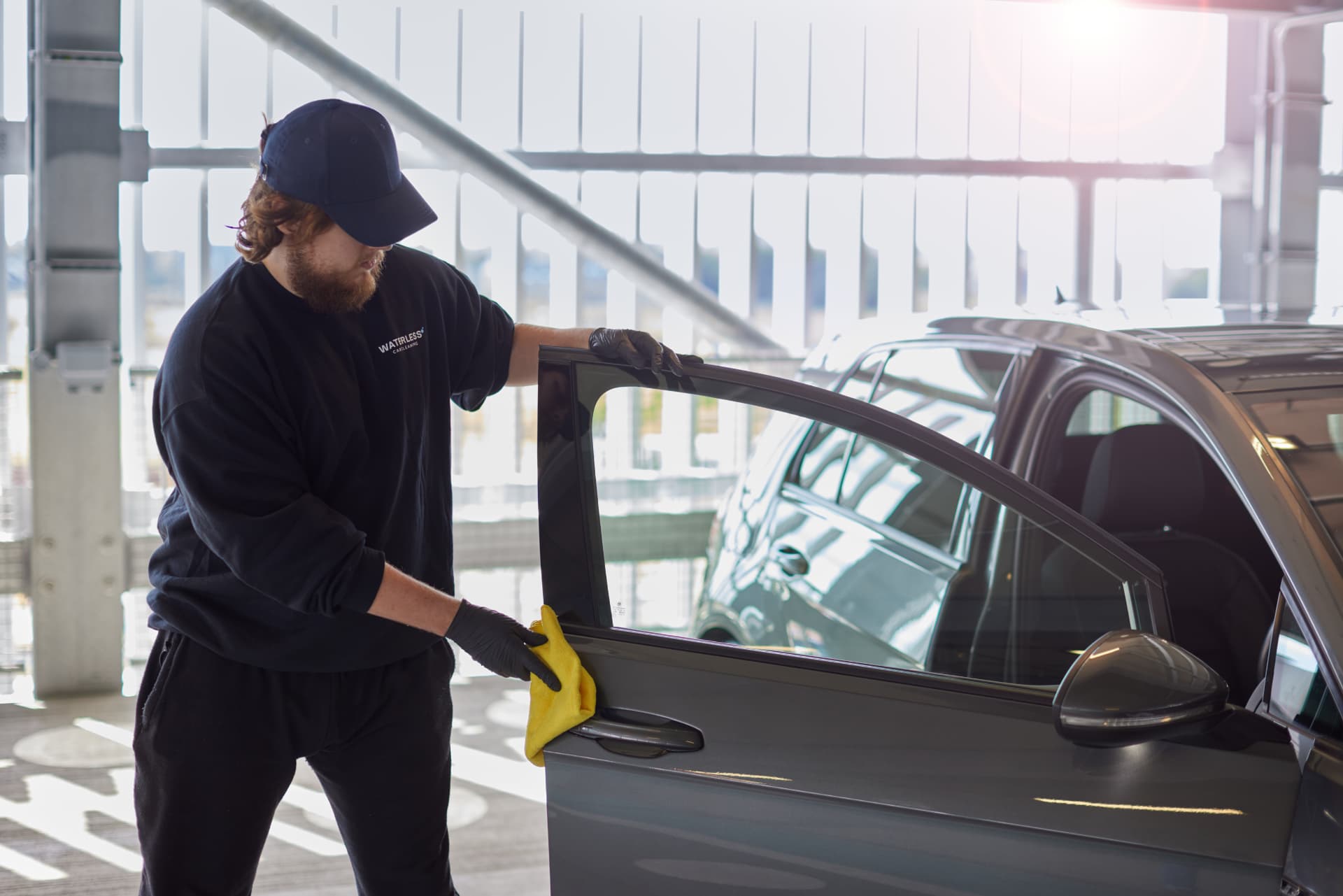 Filth technician wiping a car door frame during a waterless clean